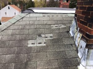 Storm damaged asphalt shingle roof with missing shingles in Burrillville, RI.