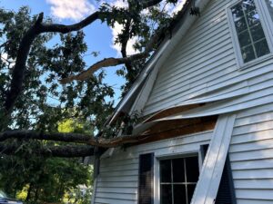 Storm damage to siding in Portsmouth, RI, caused by fallen tree branch. Repair needed along the Sakonnet.