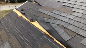 Storm damaged roof in Woonsocket, RI, showing missing shingles and exposed underlayment, indicating needed roof repair.