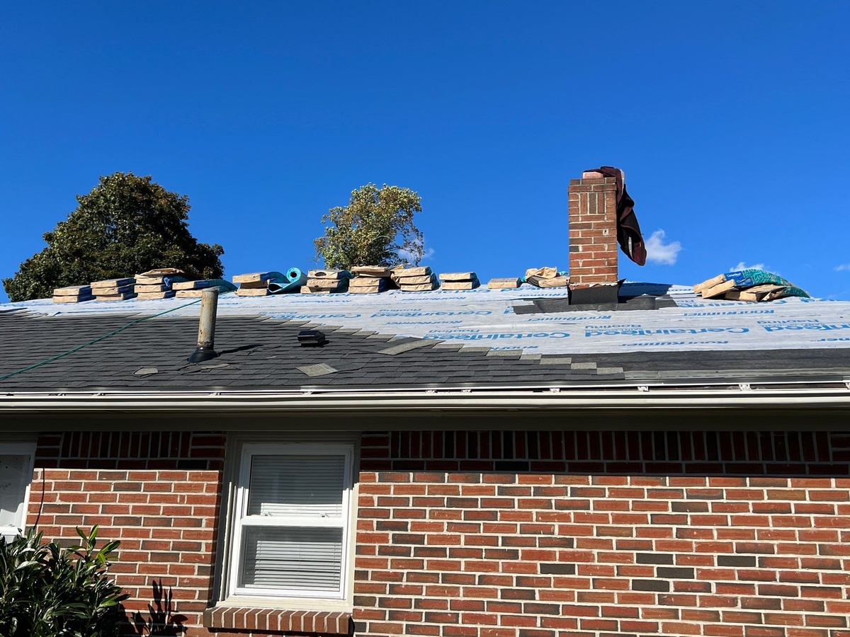 Roofing supplies staged at chimney during Cranston RI wind claim job