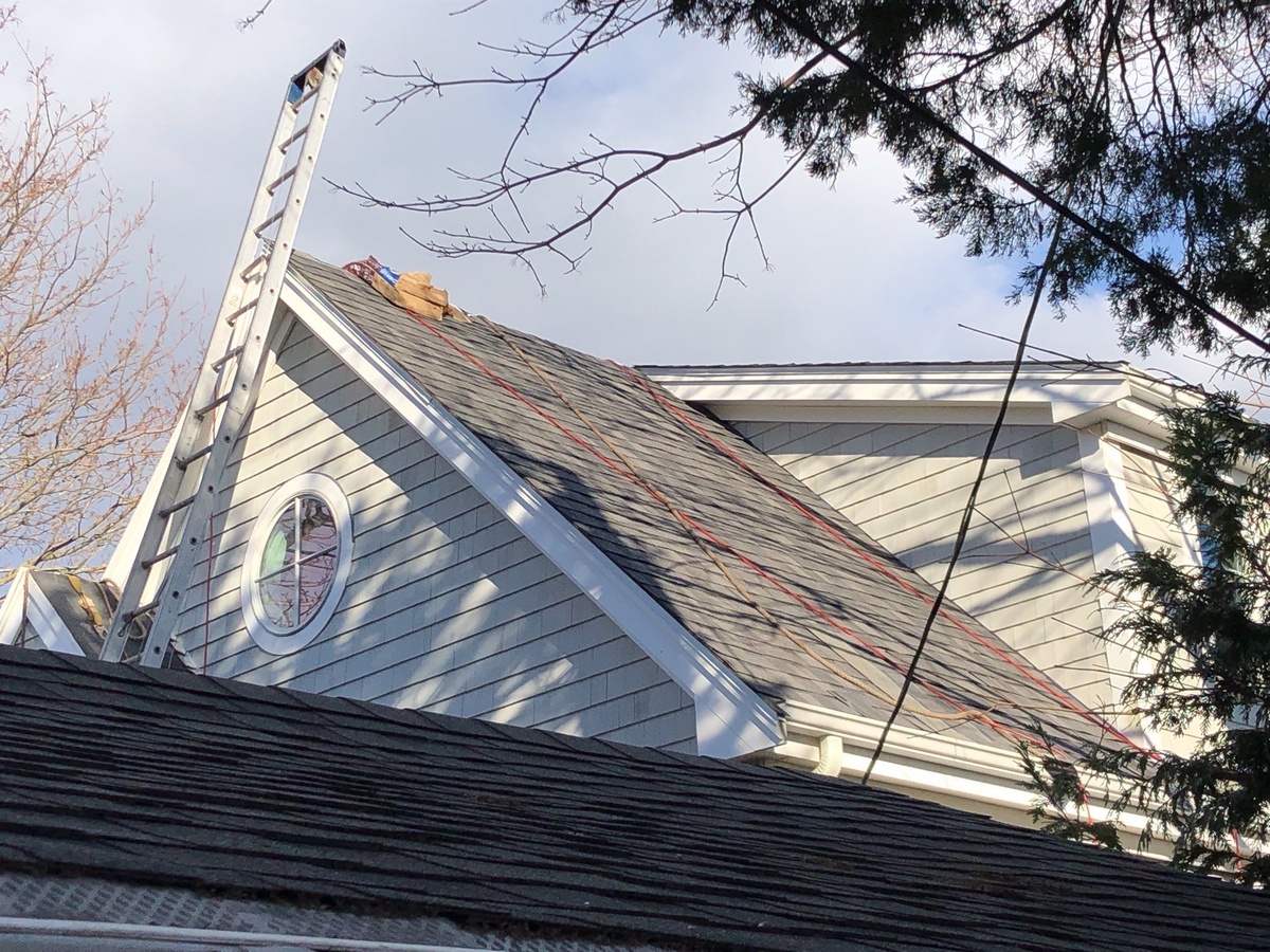 Wind-damaged shingles on Portsmouth RI roof before insurance replacement