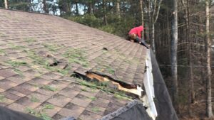 Storm damaged roof in Westerly, RI with asphalt shingles. Visible hole and debris.