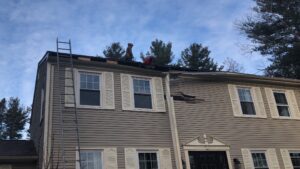 Storm damaged roof repair in Little Compton, RI, with workers on a partially removed roof.