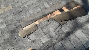 Storm-damaged asphalt shingle roof with missing shingles in Warren, RI, showing exposed underlayment.