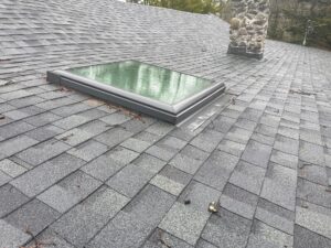 New Velux skylight installation on a Glocester, RI home with asphalt shingle roof and stone chimney.