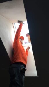Skylight install in Hopkinton RI showing worker smoothing plaster around the frame of the new Velux skylight.