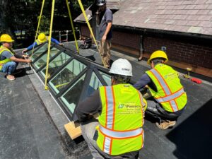 Commercial skylight installation in Providence, RI, showing workers securing a large Velux skylight on a flat roof.