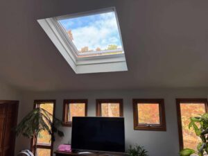 Interior view of Velux skylight installation in South Kingstown, RI, showing blue sky and autumn trees.