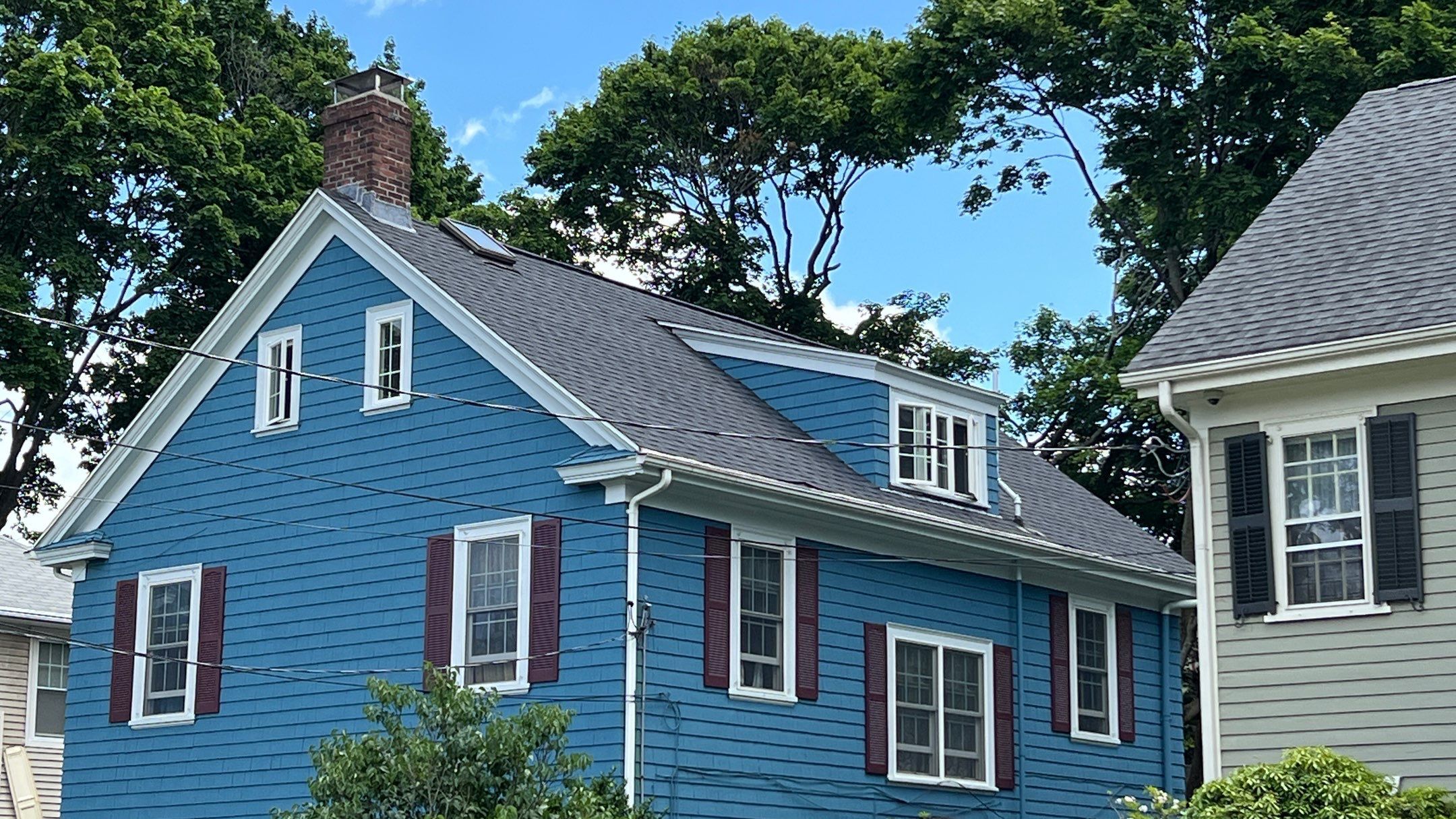 Corner view of finished gray roof and dormers on blue home, Providence roof repair