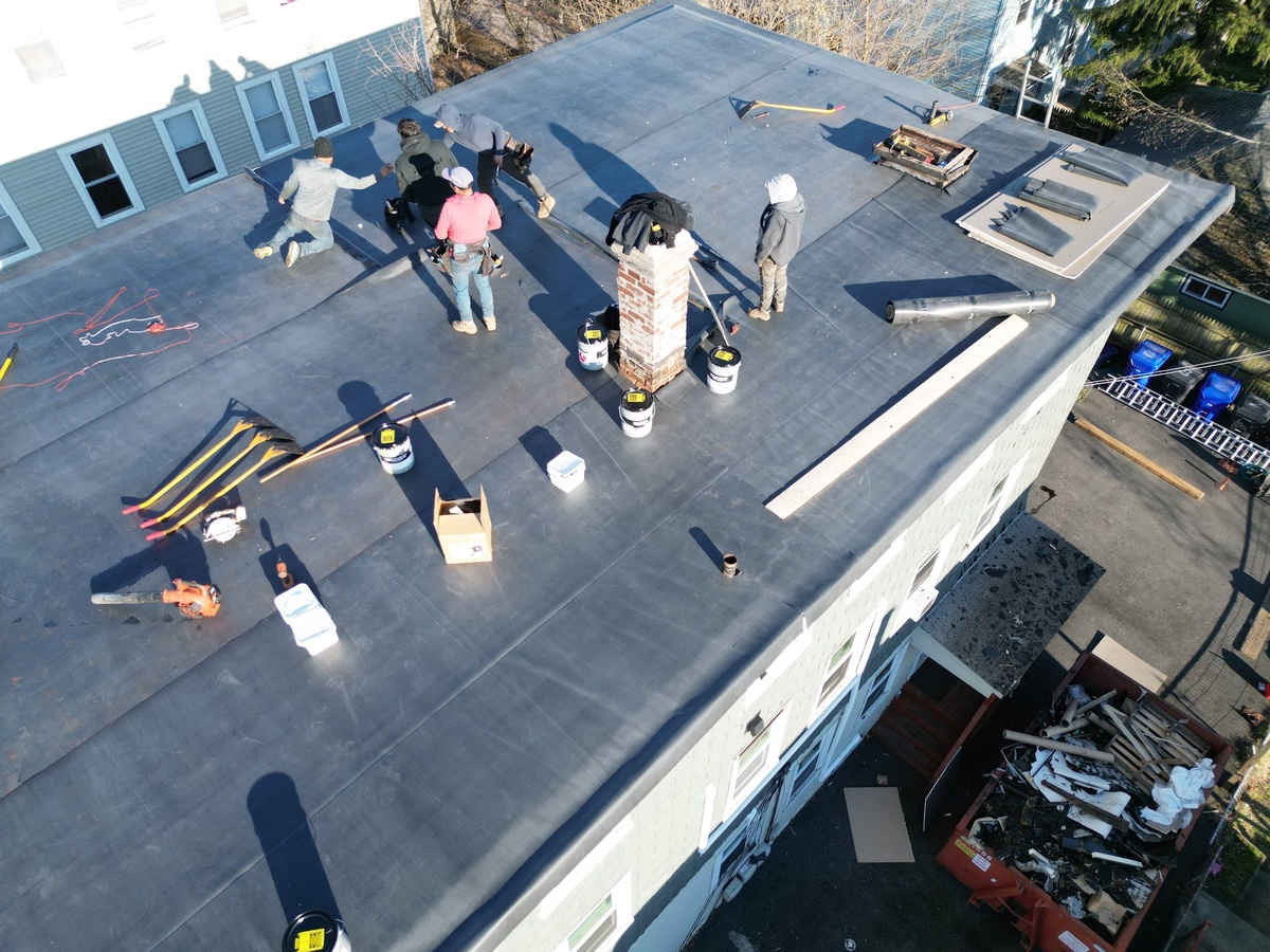 Crew installing EPDM rubber membrane roof North Providence RI triple decker